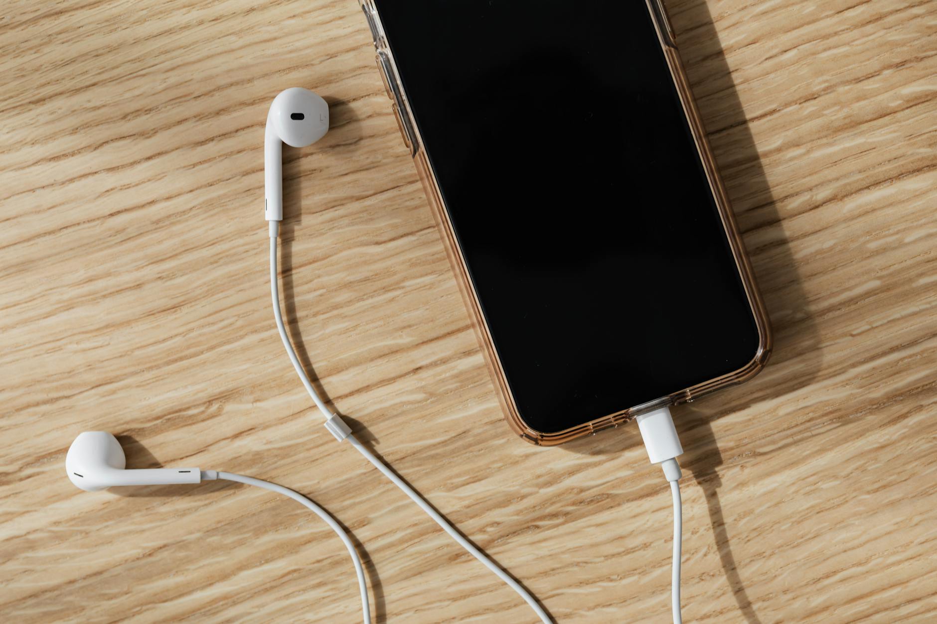 white earphones connected to smartphone